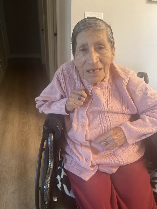 A resident smiles from her wheelchair in the hallway.